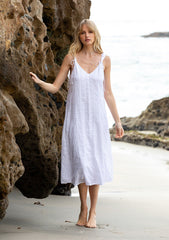 [Color: White] A model wearing a bohemian cotton white mid length dress with tank top straps and a v neckline in front and back.