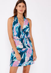 [Color: Teal/Dusty Orchid] A brunette model wearing a tropical leaf print sleeveless mini dress with a surplice v neckline and  racerback. A lightweight mini dress with a vibrant print perfect for vacation and casual outings.