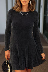 Woman wearing the Black Glittery Flare Hem Mini Dress-FINAL SALE, holding a black handbag near a building outdoors.