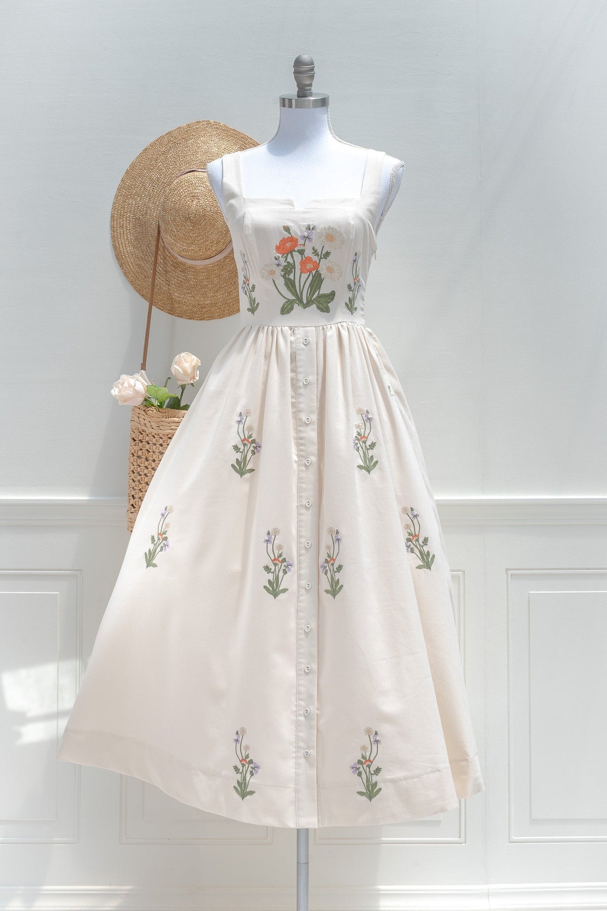 Cream cotton midi dress with floral embroidery on structured square neckline bodice and button front skirt front view.