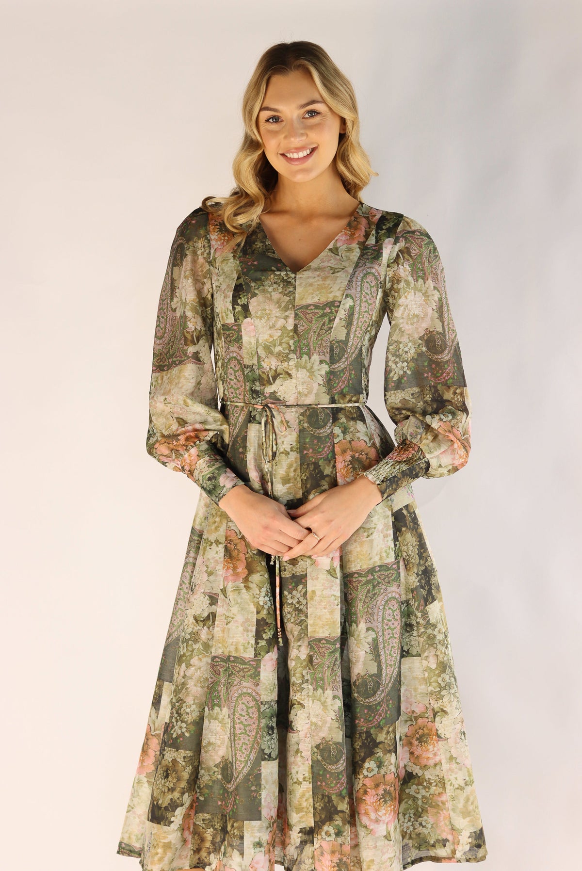 Woman wearing a long floral dress against a plain background
