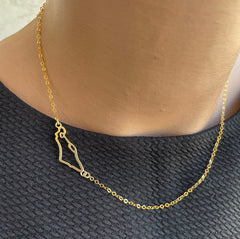 A gold-filled necklace featuring a Israel map charm, displayed on a person's neck.