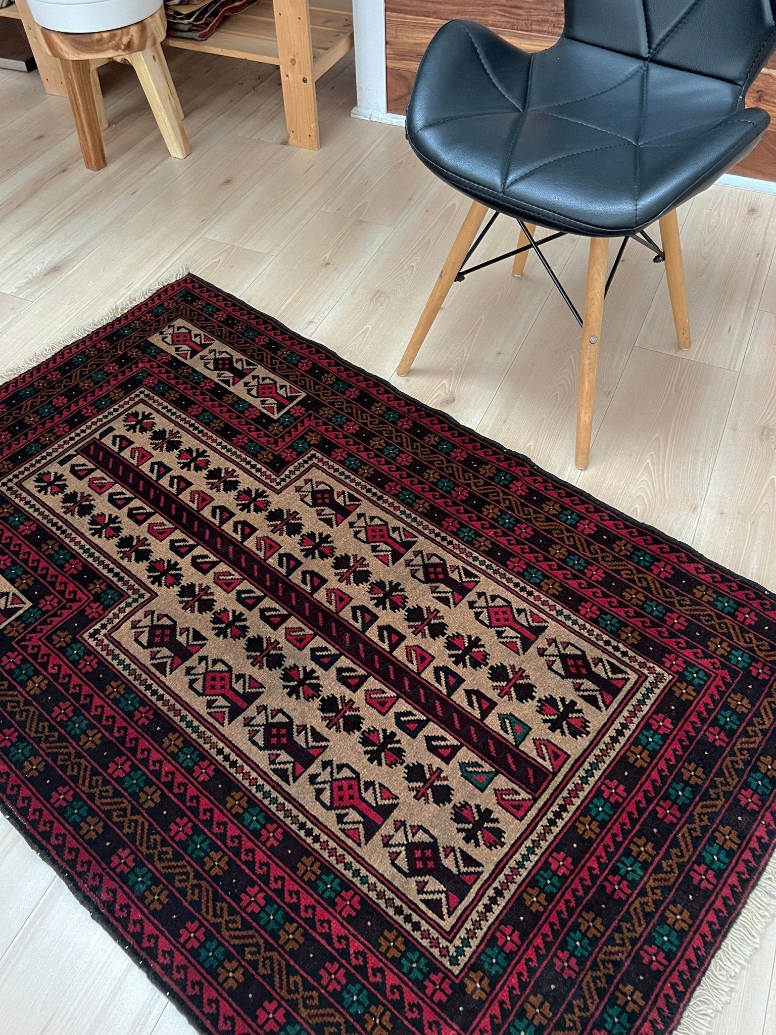 Side view of a Baluch Turkmen Prayer Rug - Handmade Wool Carpet in a 3x5 size, featuring traditional tribal geometric patterns with rich red, black, beige, green, and teal colors. Ideal for living room, bedroom, kitchen, entryway, or nursery decor. Available at a handmade rug shop in the San Francisco Bay Area.