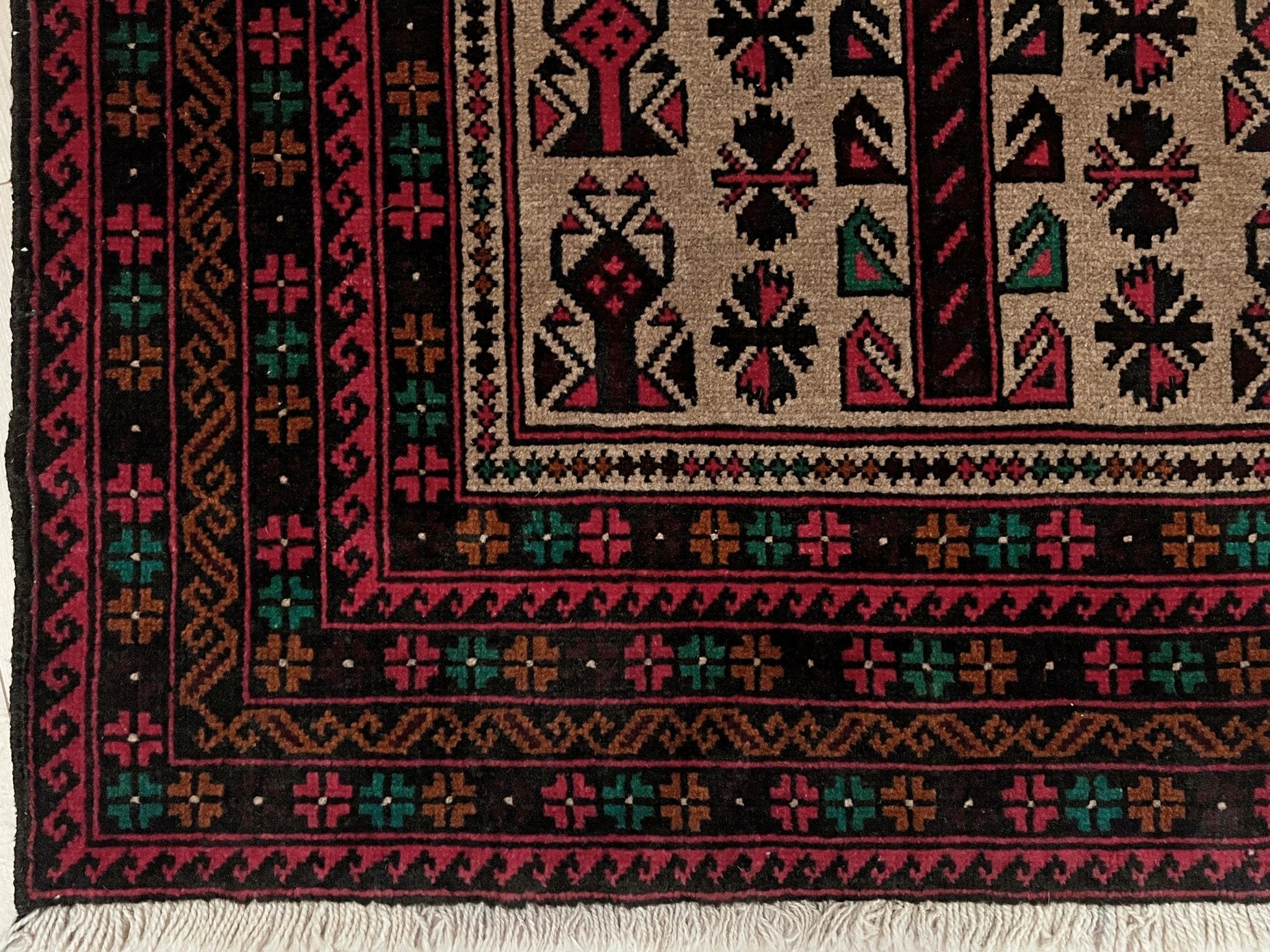 Corner of a Baluch Turkmen Prayer Rug - Handmade Wool Carpet in a 3x5 size, featuring traditional tribal geometric patterns with rich red, black, beige, green, and teal colors. Ideal for living room, bedroom, kitchen, entryway, or nursery decor. Available at a handmade rug shop in the San Francisco Bay Area.