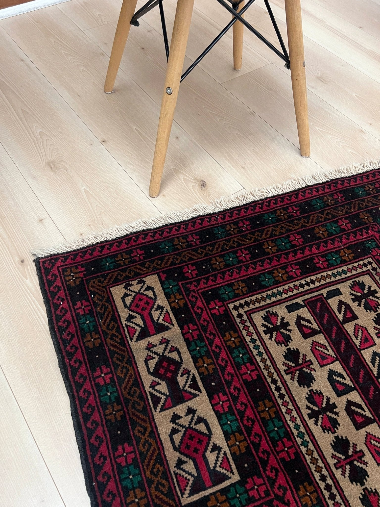 Corner picture of a Baluch Turkmen Prayer Rug - Handmade Wool Carpet in a 3x5 size, featuring traditional tribal geometric patterns with rich red, black, beige, green, and teal colors. Ideal for living room, bedroom, kitchen, entryway, or nursery decor. Available at a handmade rug shop in the San Francisco Bay Area.