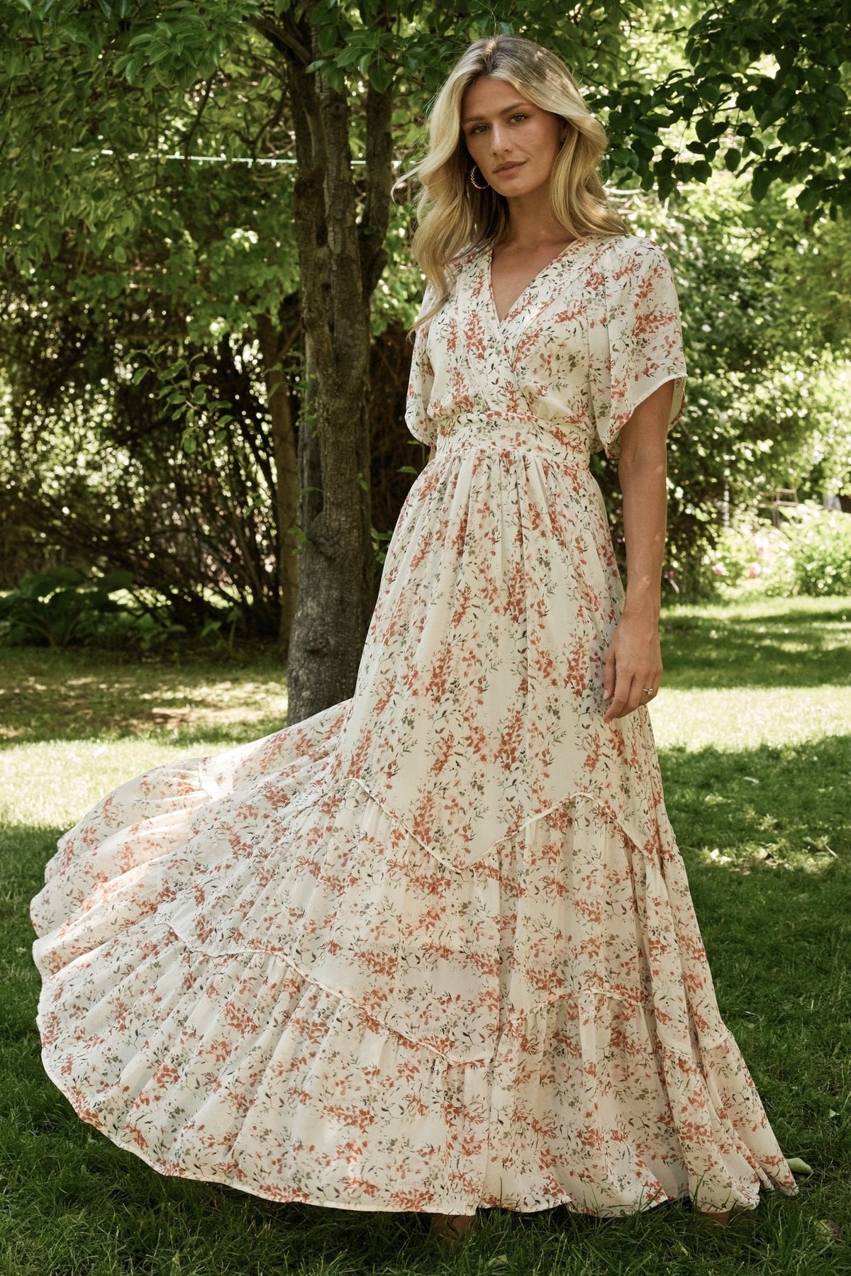 Cream and rust floral maxi dress, front view showing surplice neckline, flutter sleeves, and angled tiered skirt for movement.
