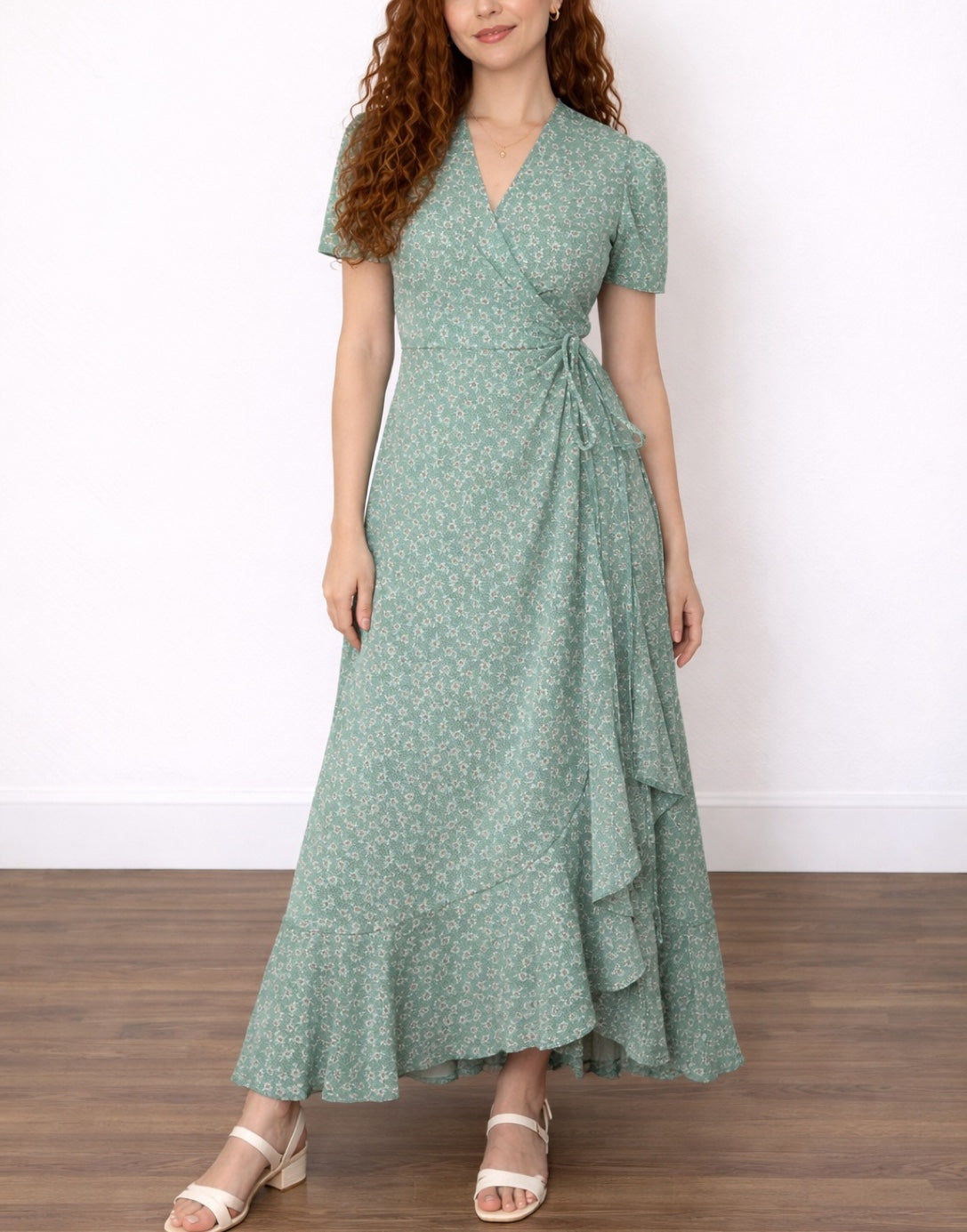 Woman wearing a green Maxi Wrap Dress with a tie and puff sleeves, standing in a plain setting.
