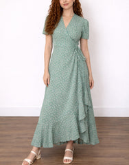 Woman wearing a green Maxi Wrap Dress with a tie and puff sleeves, standing in a plain setting.