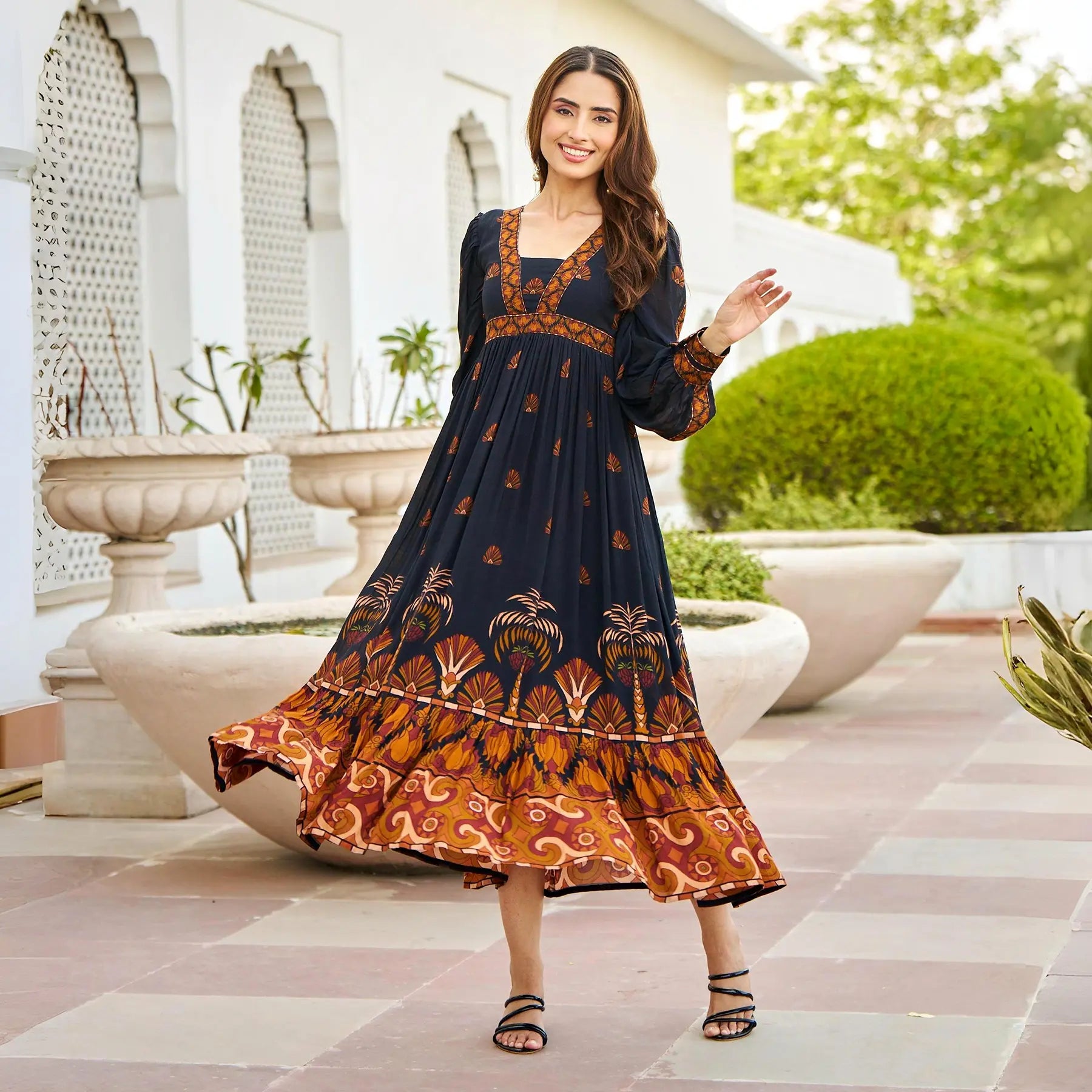 Woman twirling in a black A-line midi dress with full sleeves — perfect for festive evenings and vacations.