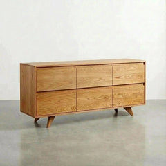 The TY Fine Furniture Modern Mid-Century Dresser in White Oak—crafted from solid wood with six drawers and angled legs—stands on a smooth gray floor against a plain, light-colored wall.