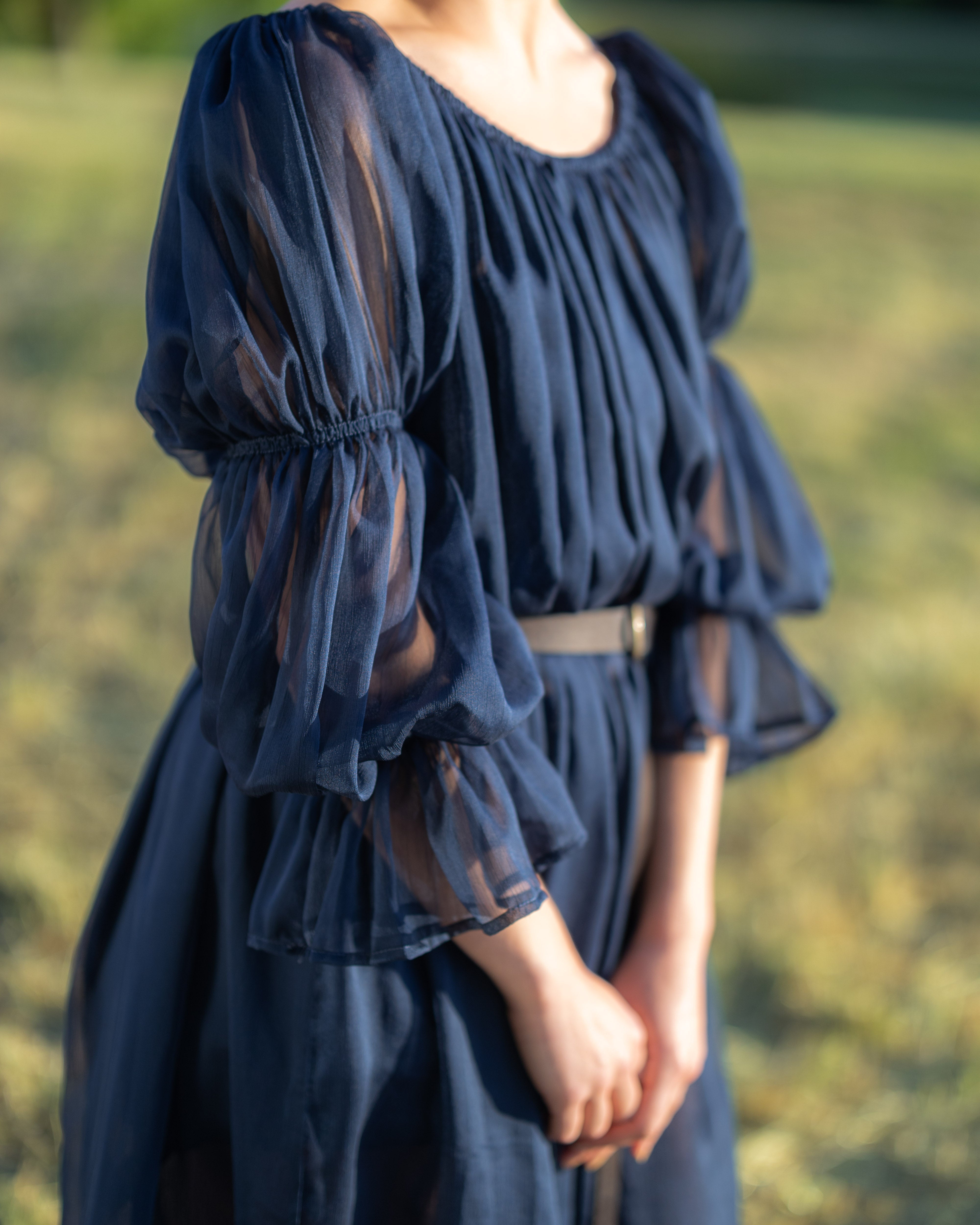 Close-up of navy blue chiffon chemise with puff sleeves and gathered elastic detailing on arms and waist.