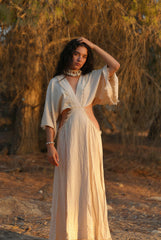 Woman in a white raw silk dress with a priestess, fairy dress feel, standing in warm sunlight.