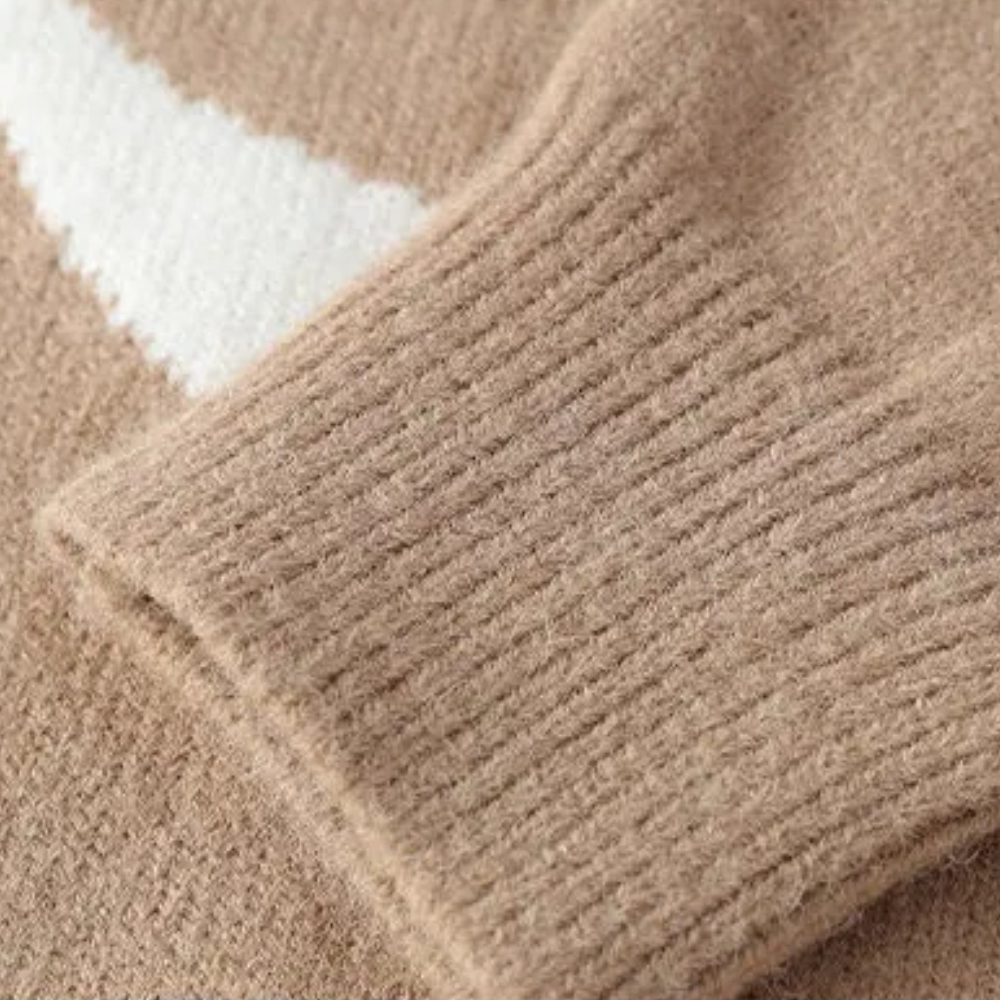 Beige strikket gensererm med ribbestrikket erme og hvit detalj. Myk ulltekstur, høst- og vintermote, komfortabelt og stilfullt design.
