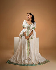 Woman wearing a white dress with green embroidery on a beige background
