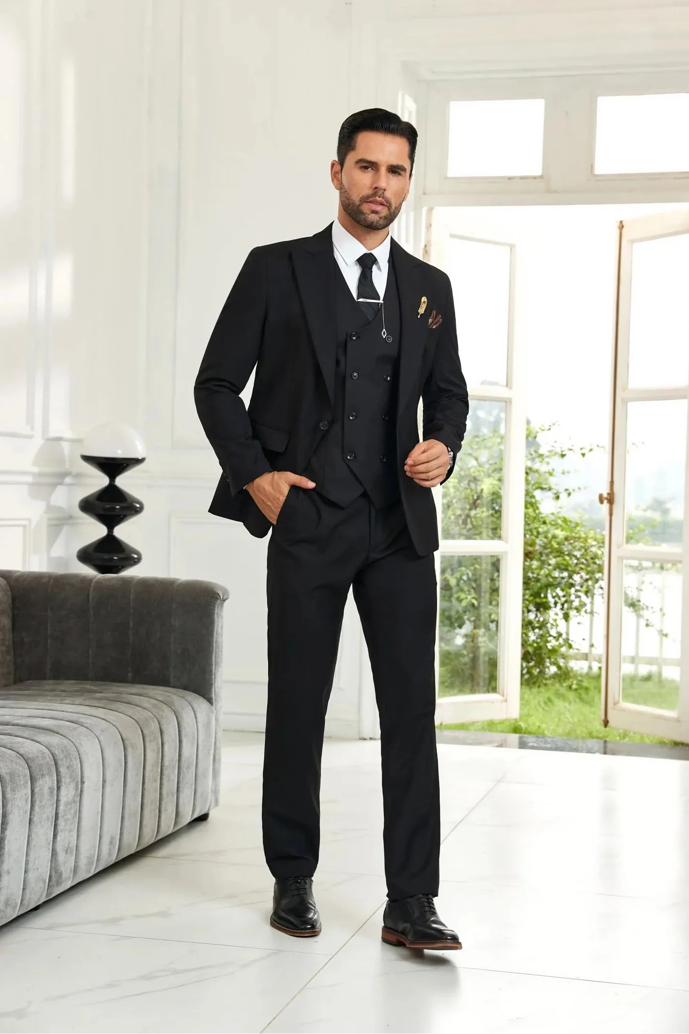 Model wearing black 3 piece men's suit with blazer, vest, and trousers in wedding formal style, front walking view.